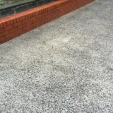 Exposed aggregate common area driveway and stormwater drain in a Sydney strata building after pressure cleaning